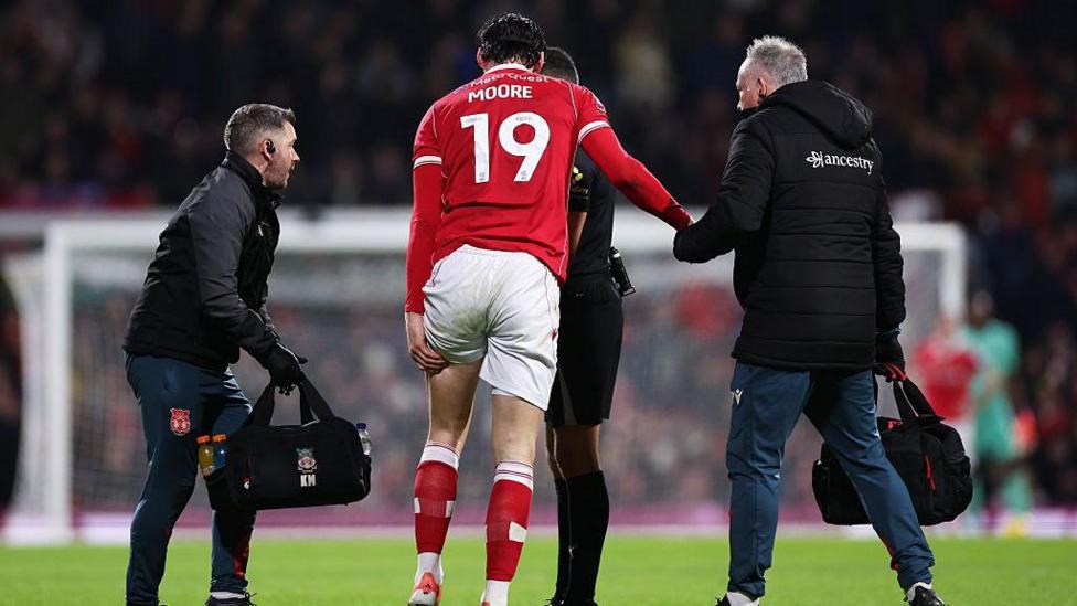 Kieffer Moore holds his hamstring and is helped by physios