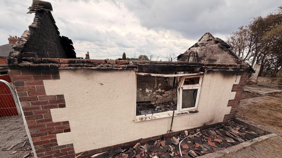 A burnt-out garage that the roof has collapsed into.