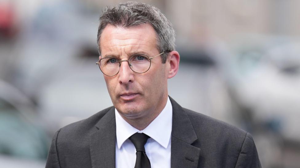 Andrew Muir, a man with grey hair, glasses, a grey suit, white shirt and dark tie.