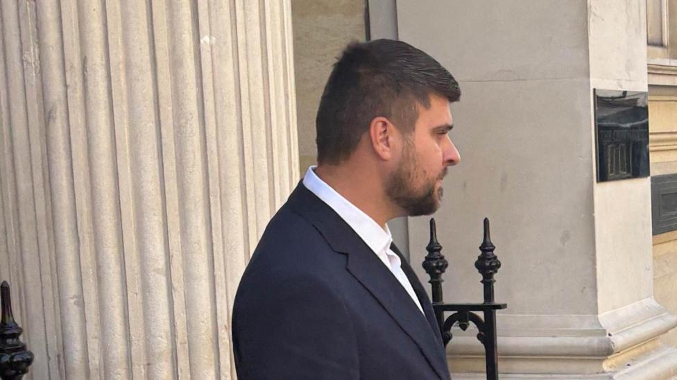 Joseph Gibson wearing a dark suit and white shirt leaves court.