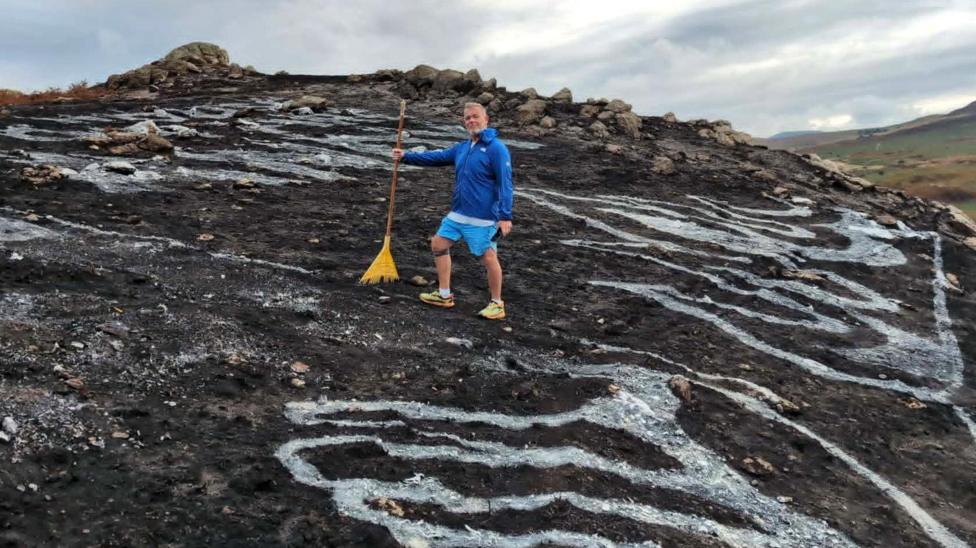 Dean Saunders in a blue top and blue shorts on a blackened mountain in yellow trainers