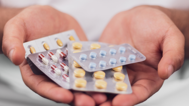 A hand holding a series of pharmaceutical drugs in packets