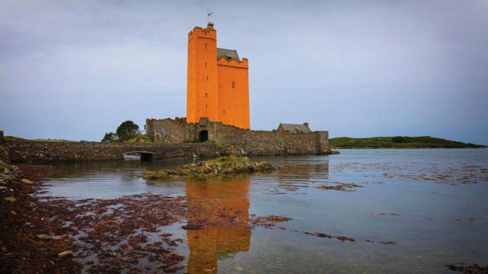 An orange castle by water.