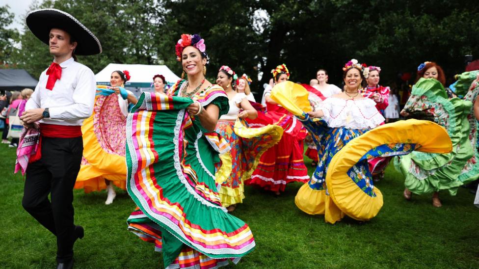 Women dancing in colourful blue, gree, yellow and red dresses