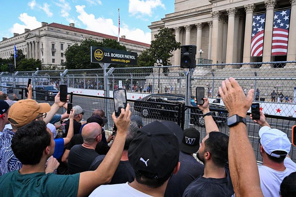 People hold up their phones to capture The Beast through the streets