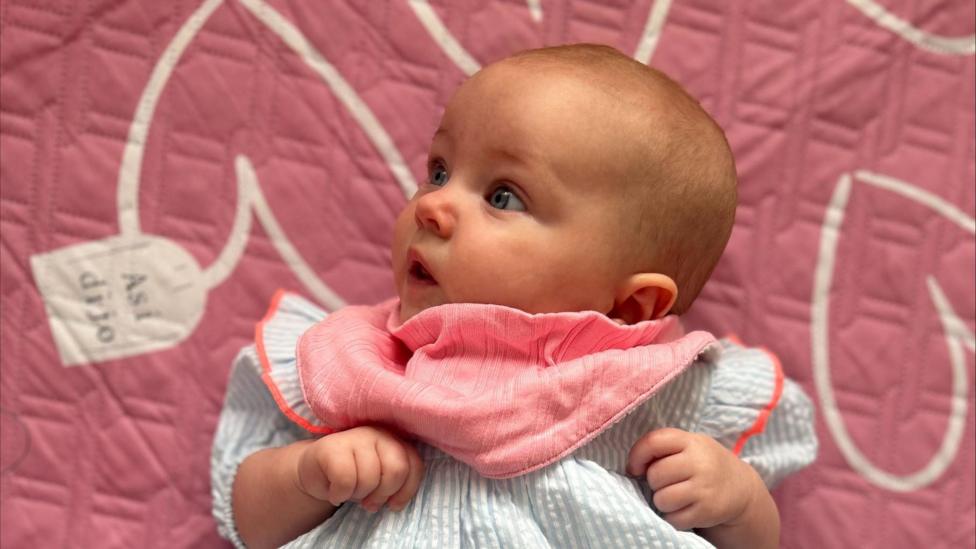 Baby in a blue and pink dress.
