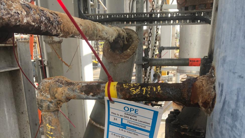 Corroded piping at the Mossmorran plant, with a label around one pipe saying "DANGER This is an OPE Break Location"