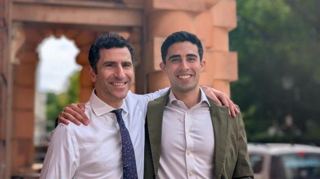 Photo of Prof Hani Marcus and Mr Danyal Khan standing outside. Both have dark brown hair. One is wearing a white shirt and blue and white tie. The other is wearing a light coloured shirt and kaki blazer.