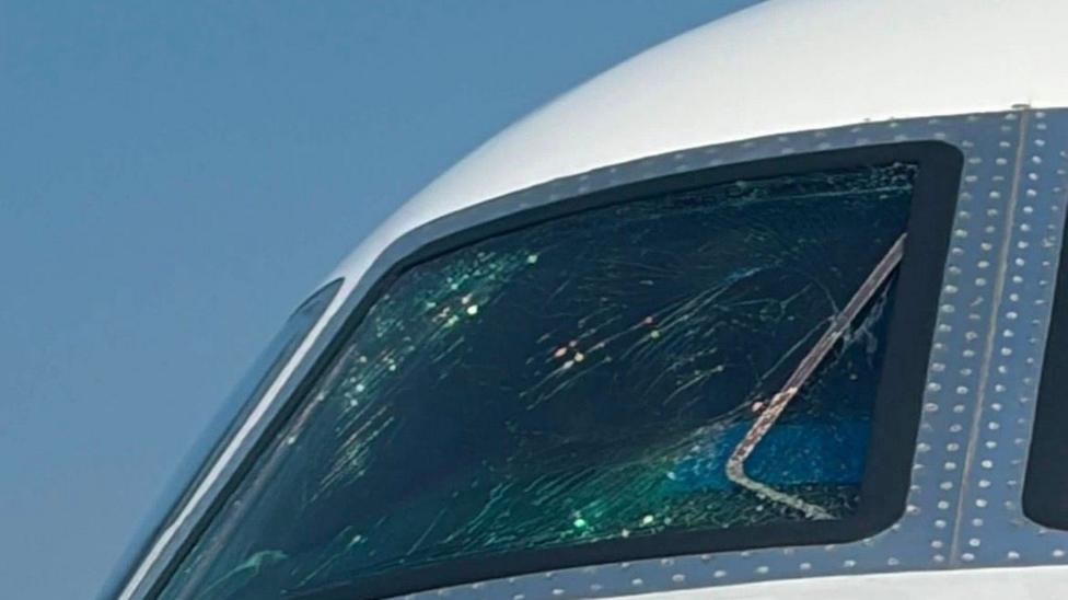 Imagine of an airplane window wit a large crack on the cockpit screen.