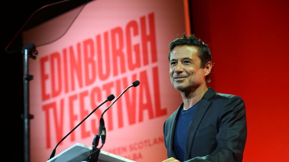 Pedro Pina, vice president of YouTube, a smart man with dark, slicked-back hair. He is wearing a dark suit jacket and T-shirt and is speaking at a lectern, the Edinburgh TV Festival logo large on the screen behind him.