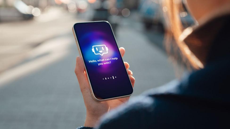 A woman holds a phone with a generic AI interface on the screen which says "hello what can I help you with?"