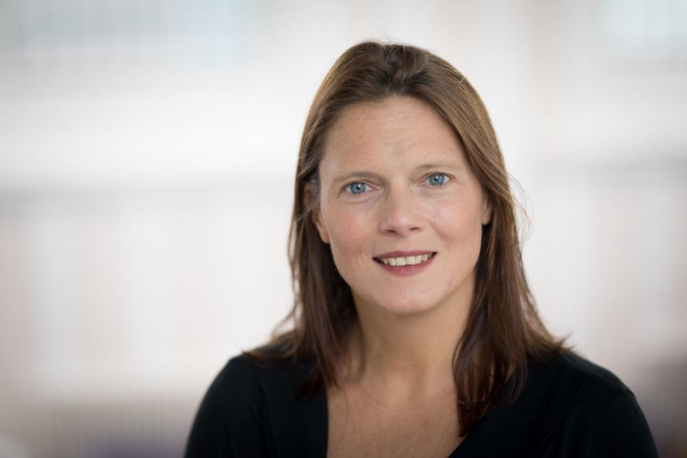 A woman with brown hair, blue eyes, smiling at the camera