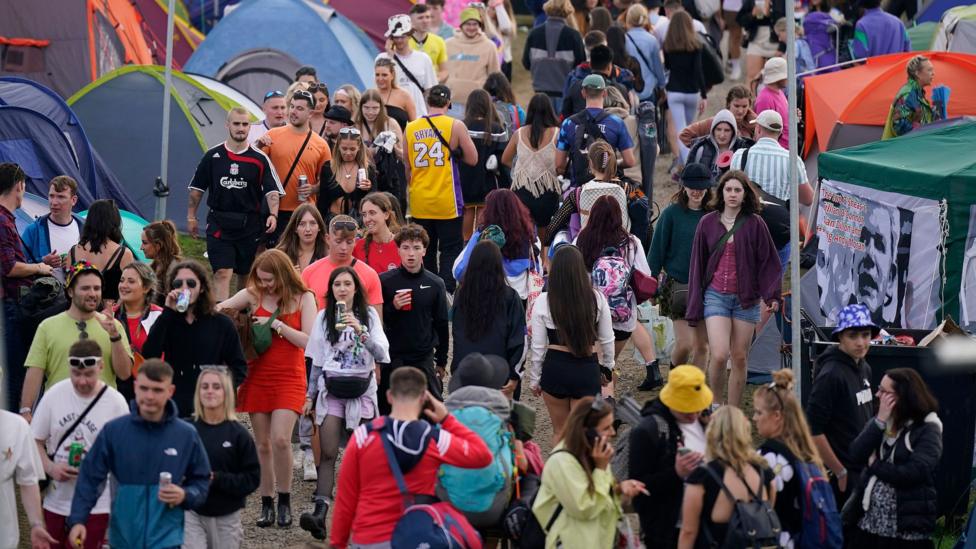 A large crowd of people attending Electric Picnic in Stradbally. Around the campsite are some large, colourful tents while attendees walk through the thoroughfare in the middle.