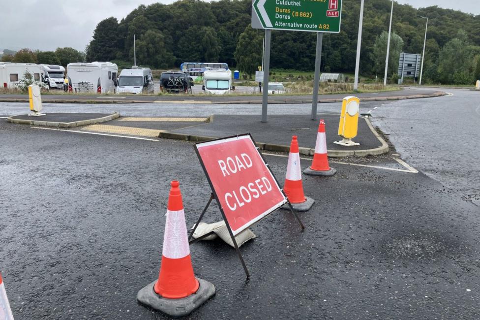 A red and white road sign that reads: "Road closed" and two traffic cones on the road to the swing bridge in Inverness.