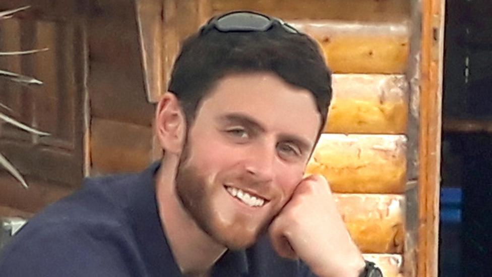 Andrew Harper is pictured - he is a man with short brown hair and a slight beard wearing a shirt and smiling at the camera.