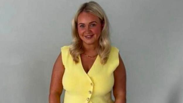 Chelsea McGillivray. She is wearing a yellow top and smiling at the camera.