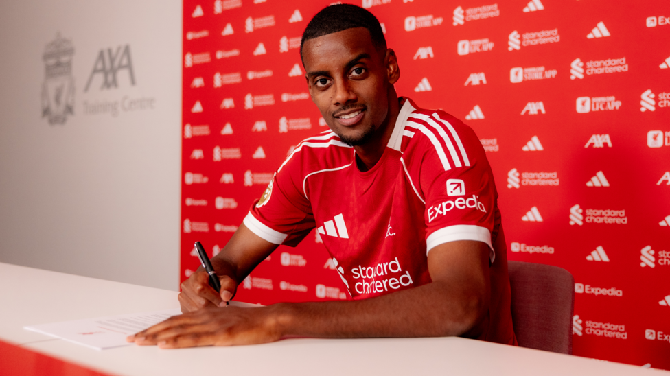Alexander Isak signs his contract in a red Liverpool shirt