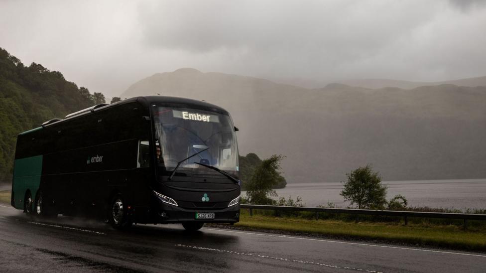 A green and black Ember bus in rain on a journey in the Highlands