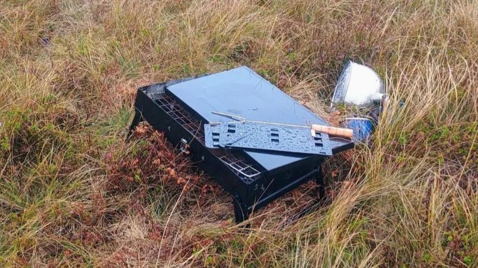 A black small BBQ sat on a patch of grass.