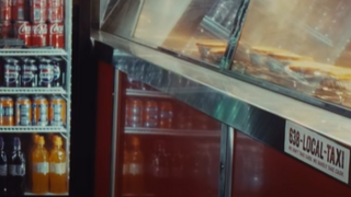 Part of a see-through heated counter with pies inside. There is a sign for a taxi with the number 638. There is also part of a fridge showing containing cans of drink.