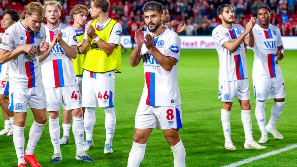 Blackburn players, wearing their white away kit with red and blue stripes down the middle, applaud their travelling fans after the 0-0 draw at Lincoln