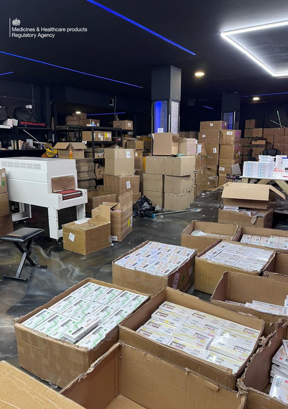 An interior shot of a factory showing boxes of drugs. Cardboard boxes are open showing unlicensed medication in little white boxes