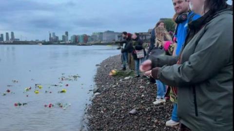 Members of the public throwing flowers into the River Thames in memory of Marmalade the harbour seal