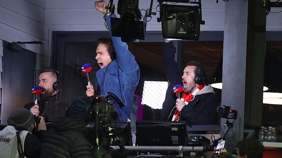 Ryan Reynolds and Rob Mac celebrate in the commentary box during Wrexham's win over Swansea in March