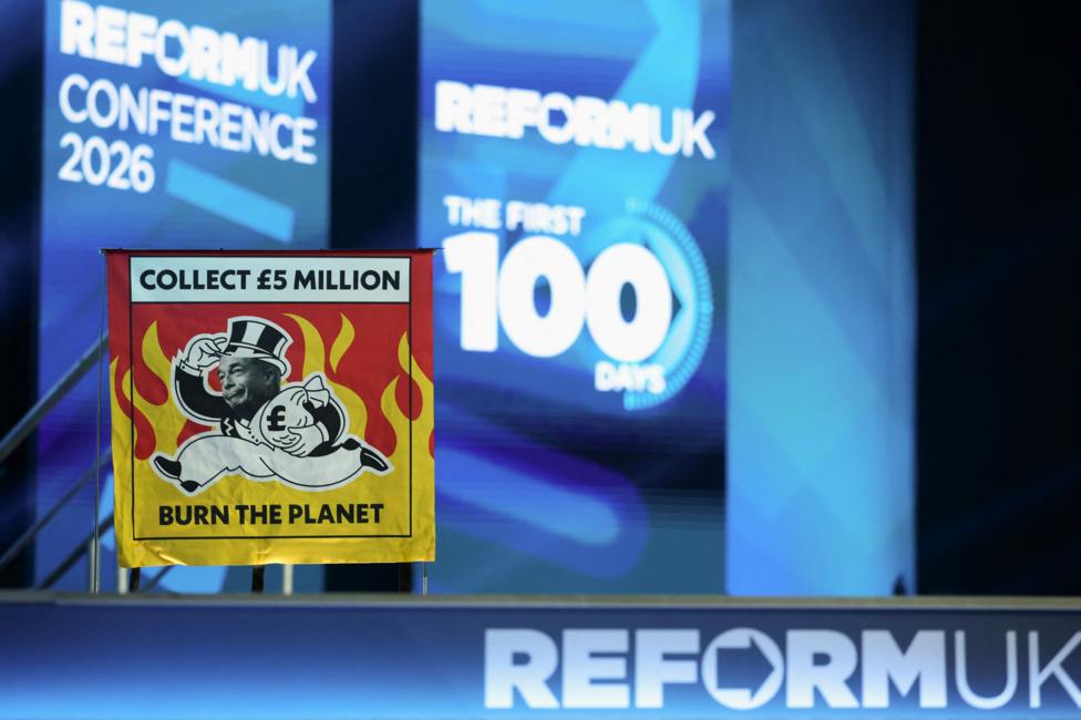 A banner saying 'collect 5 million, burn the planet' in red and yellow. the background is blue and white saying reform conference the first 100 days