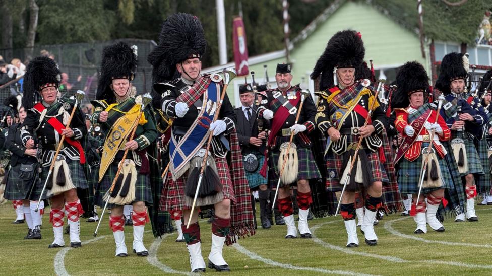 a pipe band marching on a grass running track
