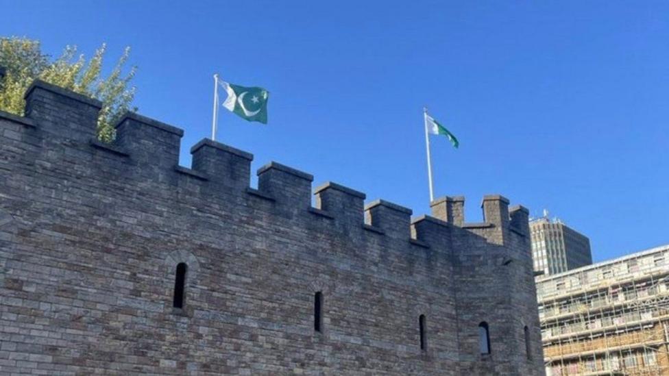 Two green and white Pakistan flags, with a crescent moon and star, on flagposts on top of Cardiff castle