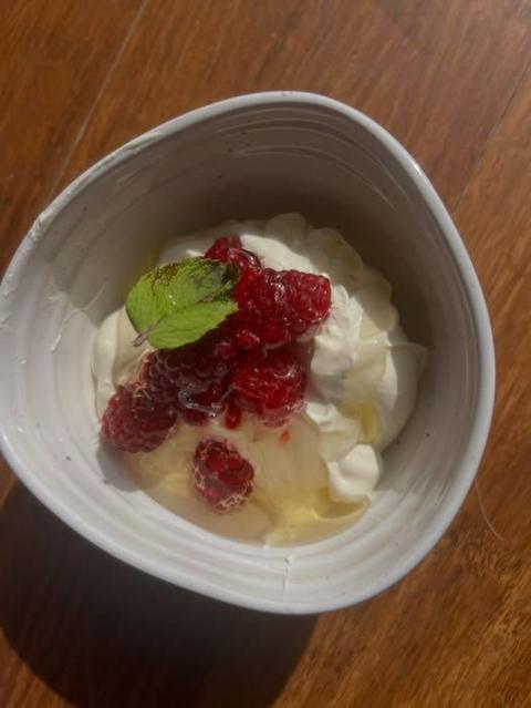 A bowl of whipped cream with raspberries and honey