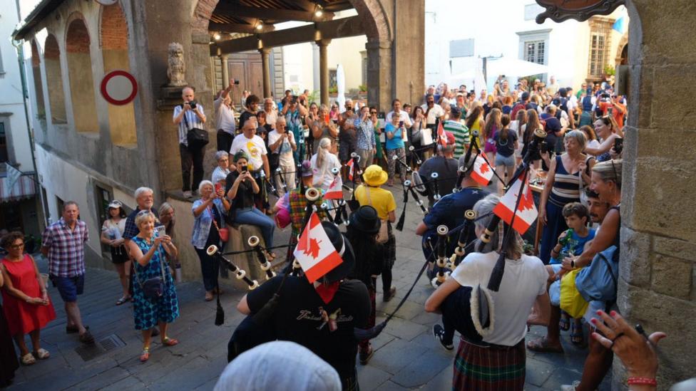 A large group of people gather to watch a Canadian pipe band in action