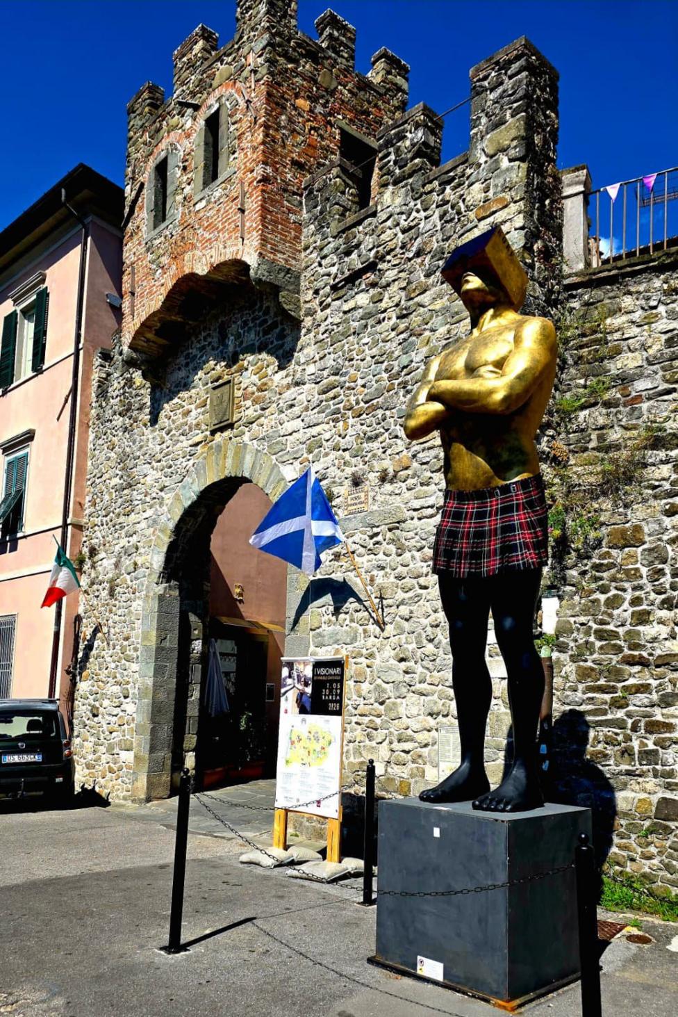 A large golden statue of a man has a kilt on it