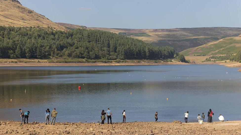 People line the banks of Dove Stone Reservoir as low water levels continue