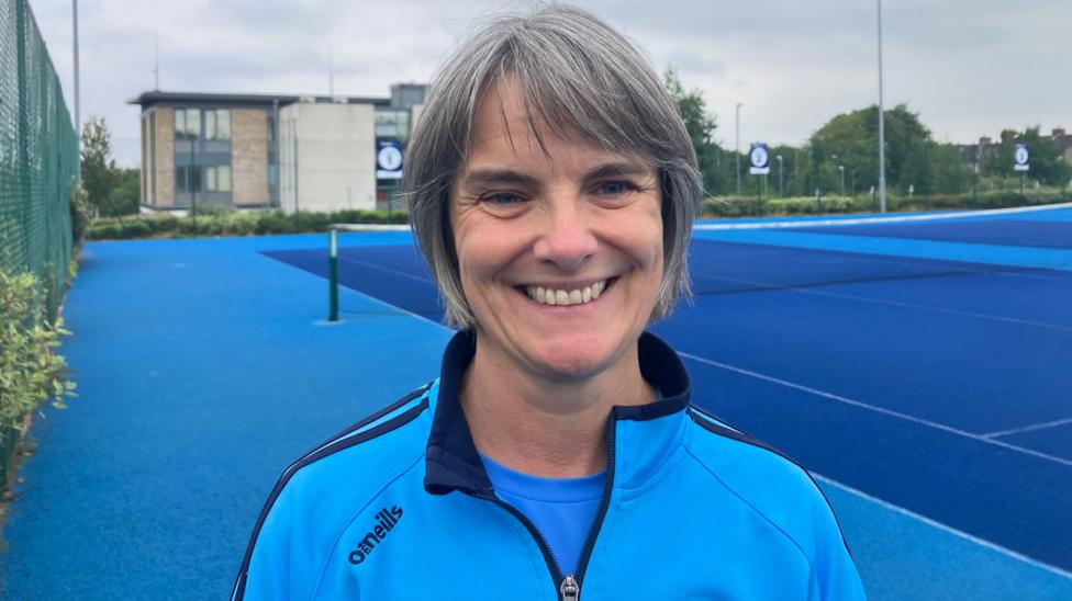 A woman with short grey hair wearing a blue 1/4 zip