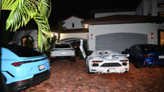 Several supercars parked in the courtyard of a large villa