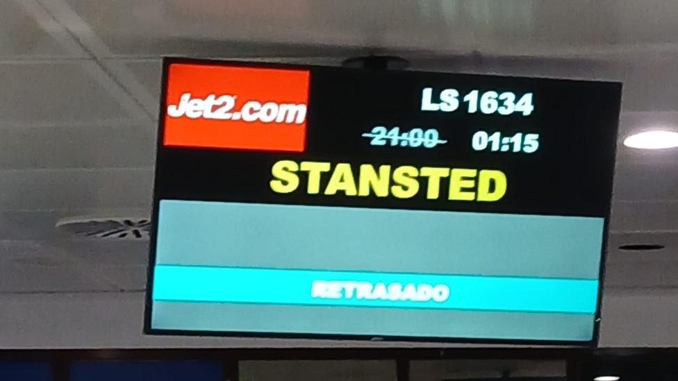 A departure board that shows the flight to Stansted as delayed to 1:15 instead of its original time of 21:00