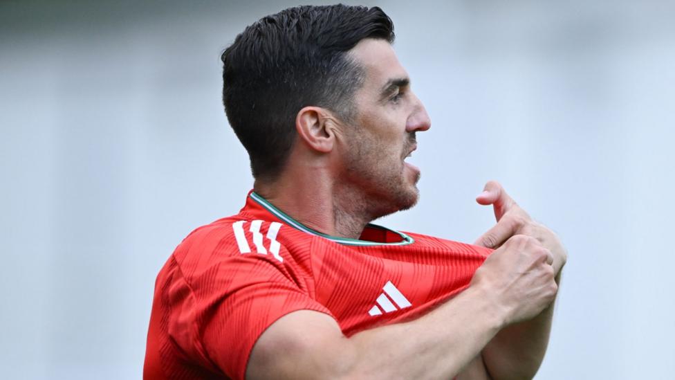 James Taylor pulls the badge on his shirt playing for Wales