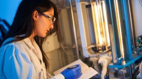 A lab worker at Powall takes notes while looking at equipment.