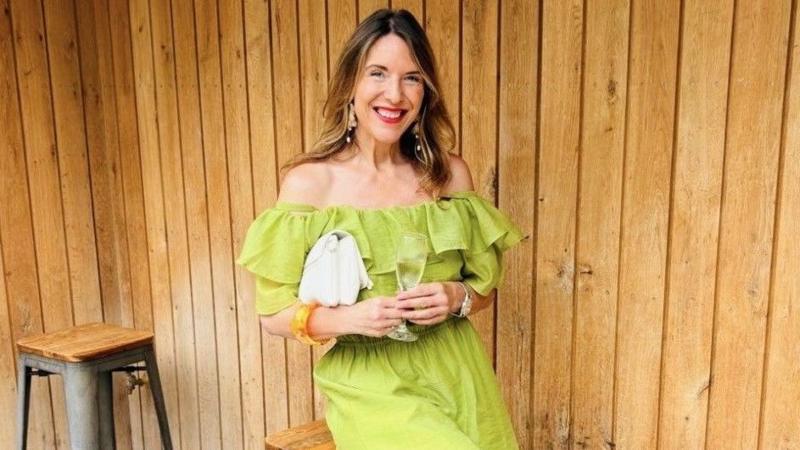 Anna-Louise Dearden sits on a bar stool. She is wearing a lime green dress and is smiling at the camera.