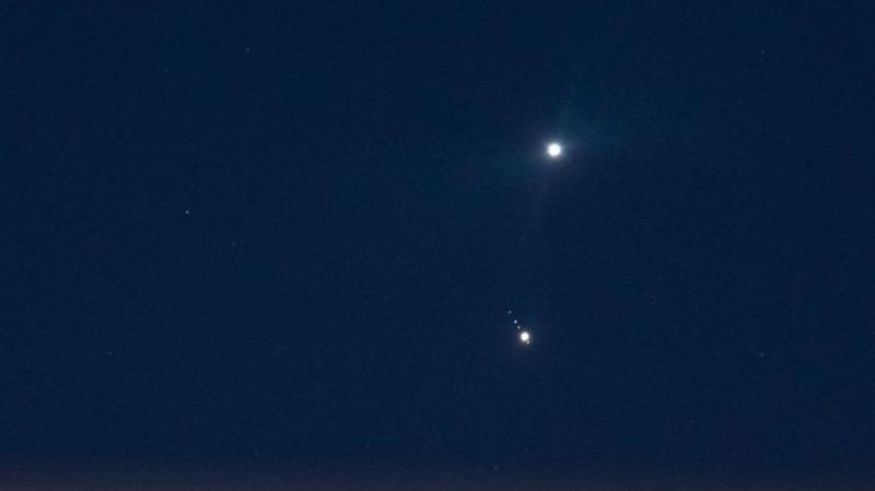 In a dark blue, almost black, sky the two planets of Jupiter and Venus shine brightly in the distance.