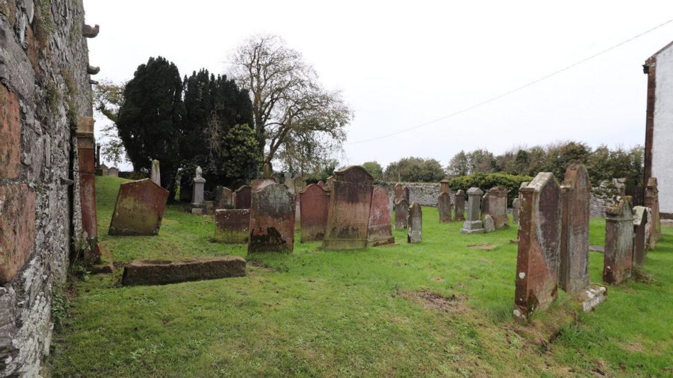 A set of old gravestones surrounded by grass