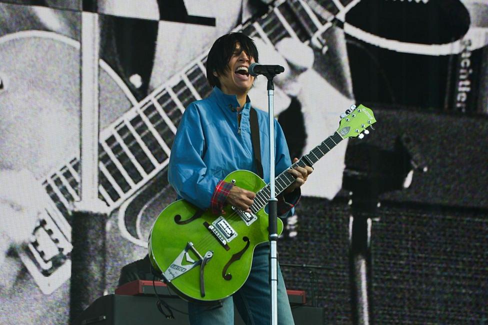 Sharleen Spiteri from Texas playing on stage. she is singing at a mic and is playing a green guitar.