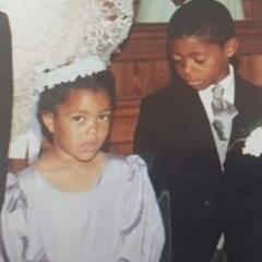 A childhood photo of Natalie and Leroy, the appear to be under 10 and are wearing formal clothes like they are going to a wedding