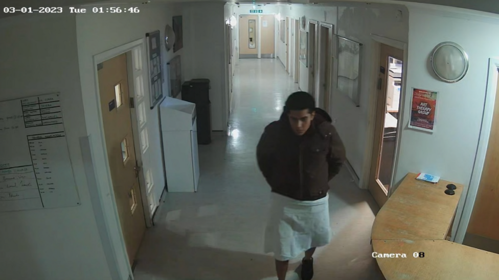 Rolando Torres-Pena walking in the unit, with his legs covered by material wrapped around his waist. 