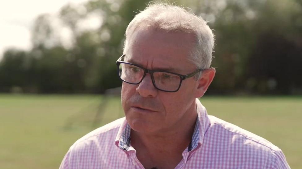 Tim McNally is chair of Piddington Parish Council. He has short grey hair and is wearing a pink shirt.