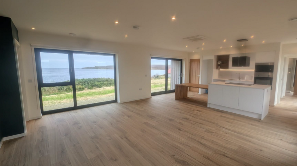 view from a kitchen out to the sea through wall to ceiling windows