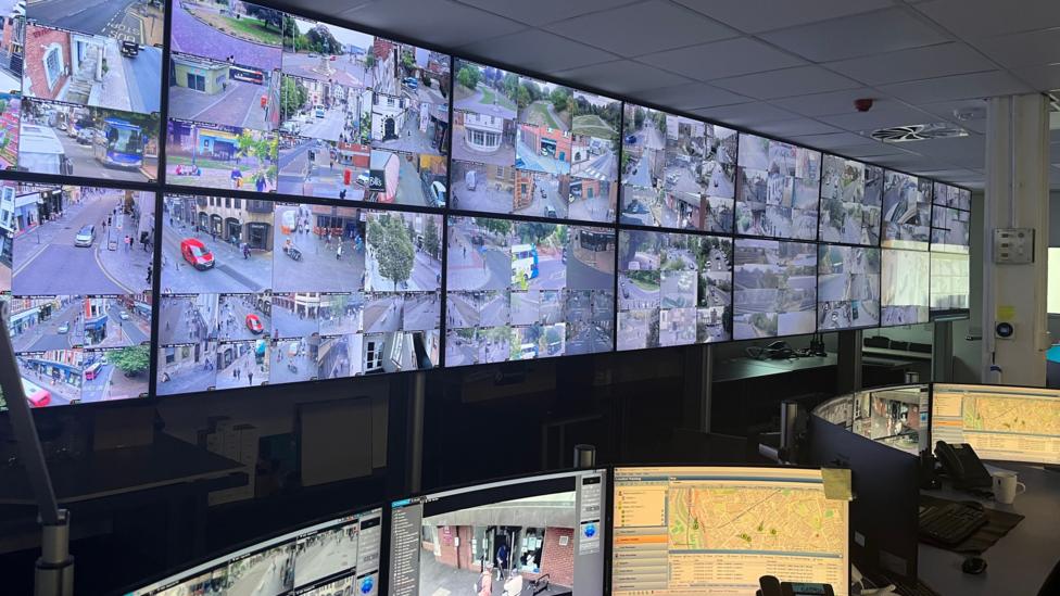 A large room showing a wall covered with screens from CCTV cameras around Exeter