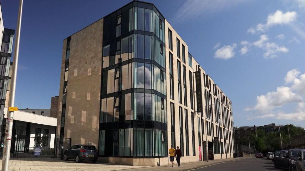 A five-story student accommodation block. It has beige walls and large windows.